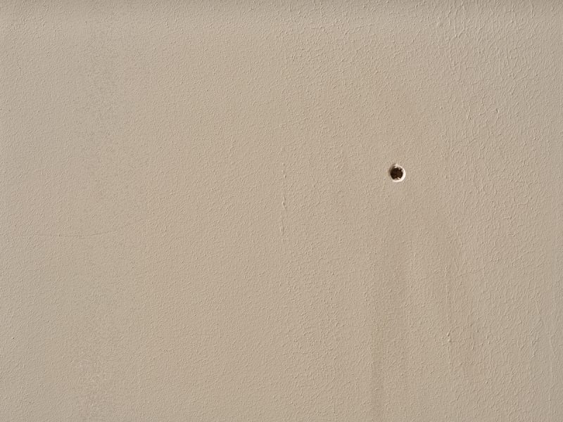 beige muur met klein gaatje erin